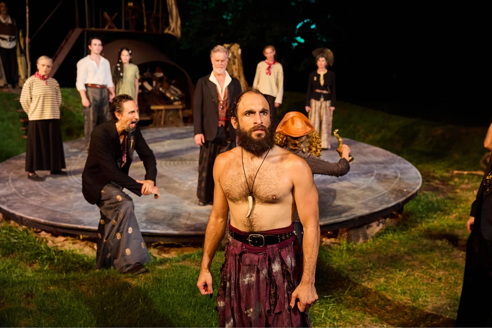 Jerreme Rodriguez as Caliban in the foreground with the company of The Tempest behind him at the Carrie Blast Furnaces