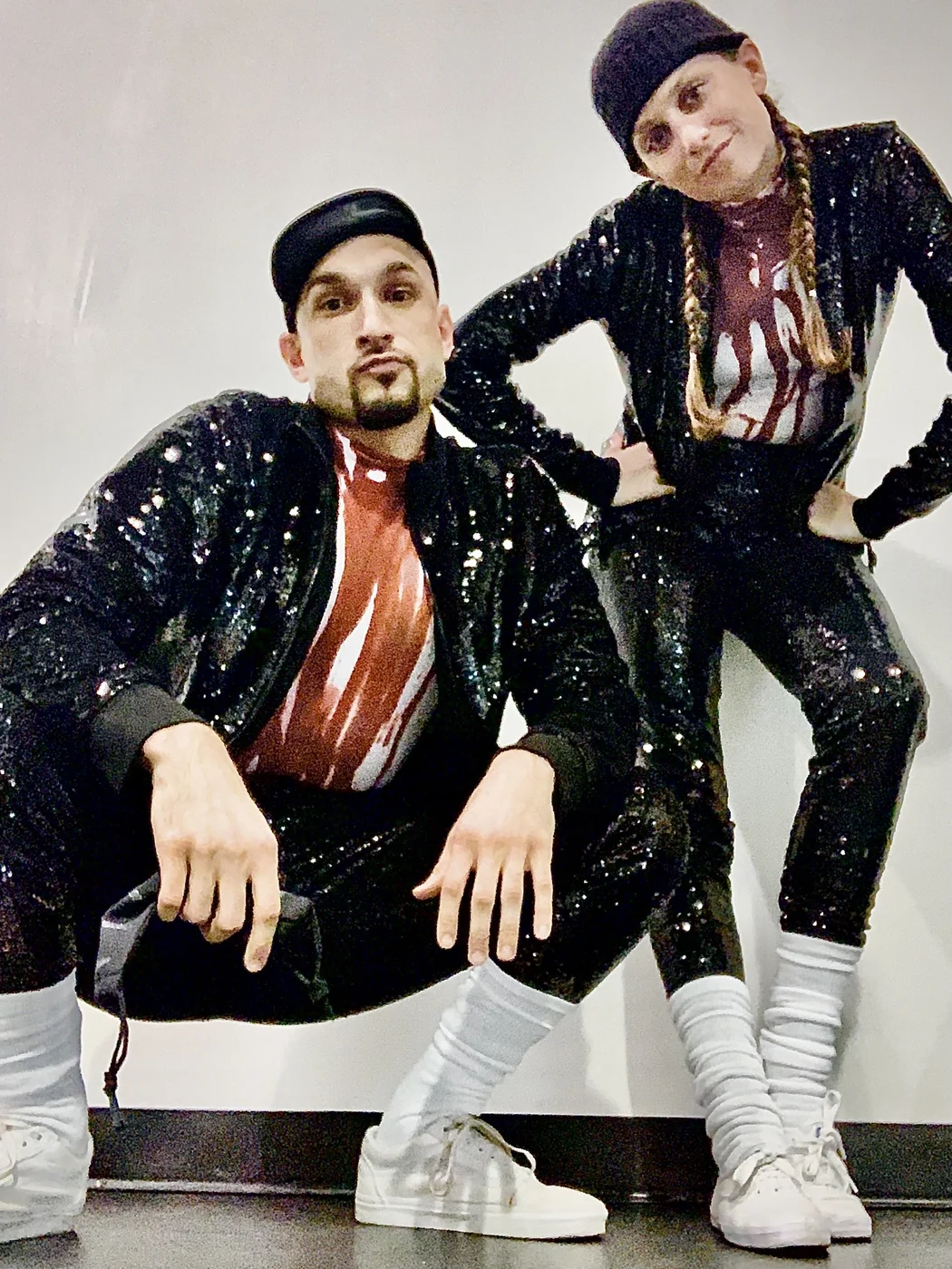 Two Undead performers posing in black sequined costumes, red-and-white shirts, and white sneakers